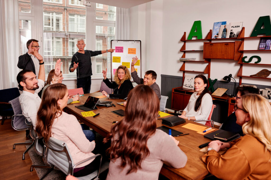 Zehn Berater von relations Hamburg sitzen an einem großen Holztisch auf einer Veranstaltung über Change Management
