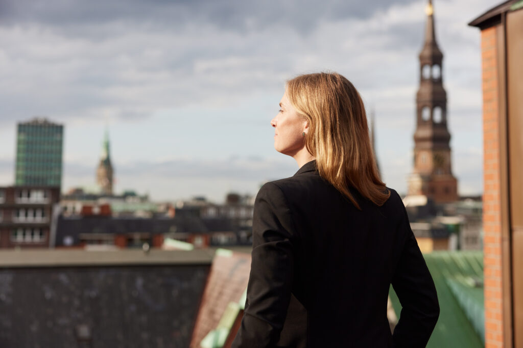 Anika Kozakow von relations Hamburg steht und sieht auf die Skyline der Landungsbrücken
