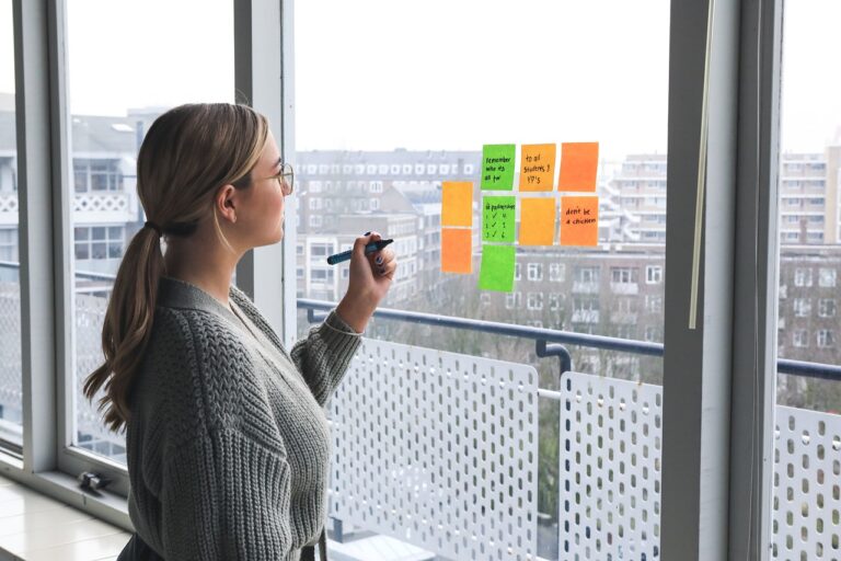 Frau plant am Fenster mit bunten Post its einen Workshop