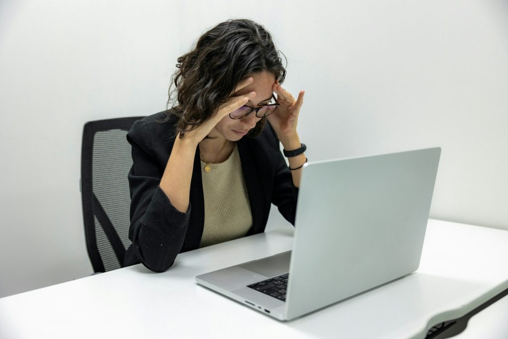 Frau vor Notebook mit Händen am Kopf