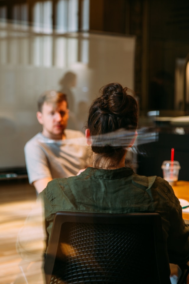 Eine Frau mit Rücken und ein Mann im Hintergrund im Büro im Gespräch